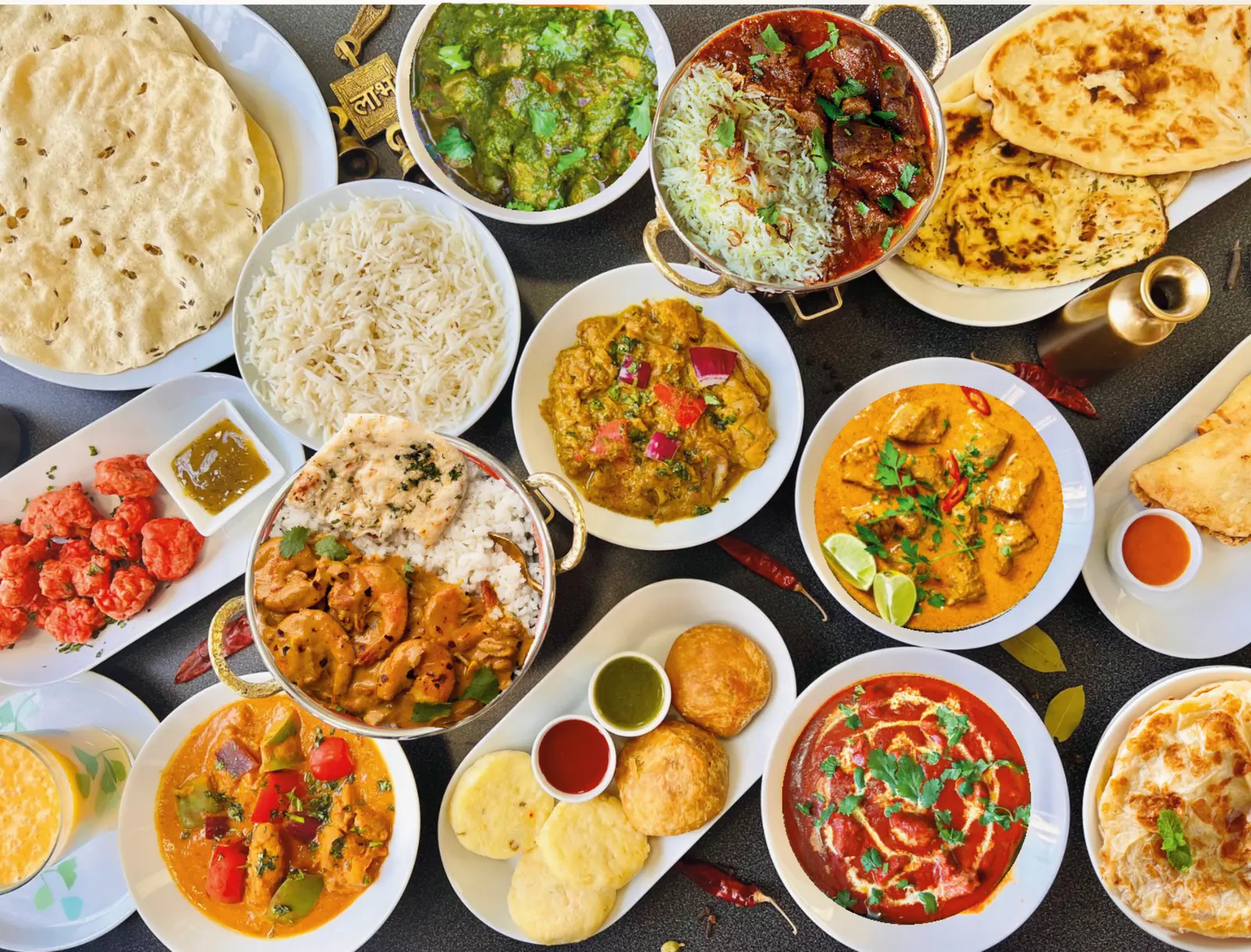 Et bord dekket med indiske retter: karriretter, biryani, naan, ris, papadam og tilbehør.